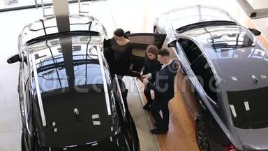 汽车推销员在展厅里和顾客交谈，给他们看一辆<strong>新</strong>车。